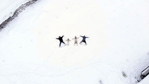 Winter family fun. happy family of 4 are making angels on the snow. aero, top view. 