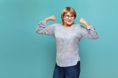 Portrait of smiling young woman against blue background