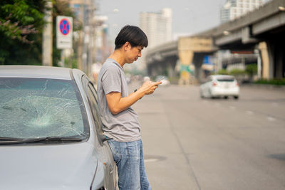 Side view of man using mobile phone in city