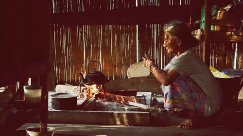 Woman preparing food on stove in hut