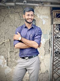 Portrait of a smiling young man standing against wall