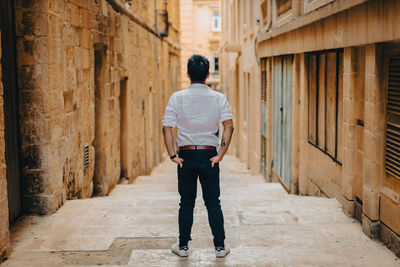 Rear view of man standing against old building