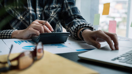 Midsection of man using smart phone on table