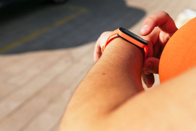 Crop unrecognizable sportswoman with curvy body watching heart rate on wearable tracker during workout on street