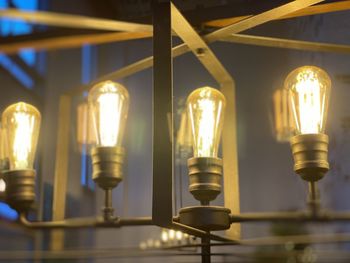Low angle view of illuminated light bulbs hanging from ceiling