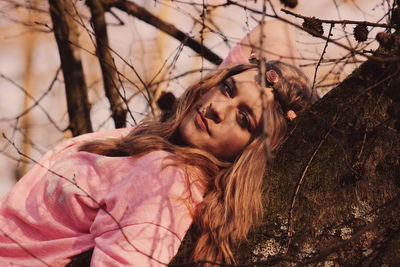 Portrait of beautiful woman reclining on tree at forest