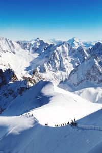 Scenic view of snowcapped mountains against blue sky