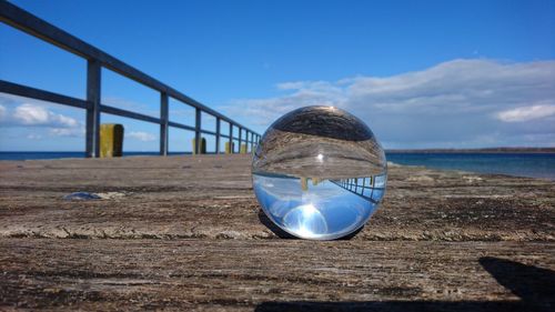 Crystal ball on beach against blue sky