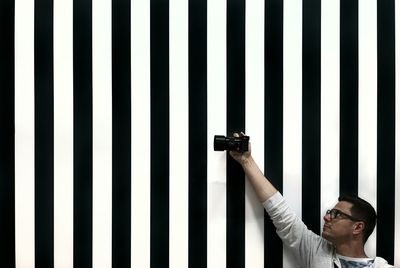 Man holding camera by striped wall