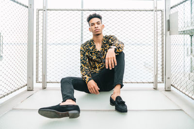 Portrait of young man sitting on wall