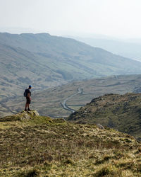 Rear view of man walking on mountain against sky