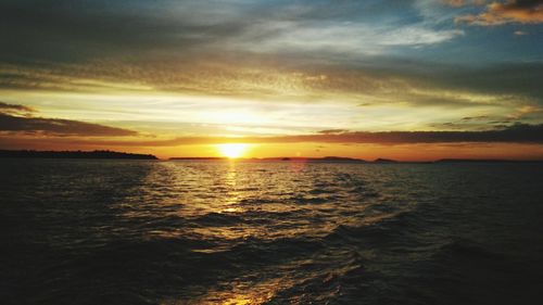 Scenic view of sea against dramatic sky during sunset
