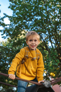 Cute little boy playing in the playground. the boy climbs onto the climbing frame. city parks.