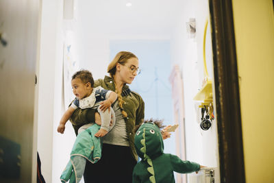 Low angle view of mother with children standing by door at home