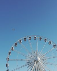 Low angle view of ferris wheel against clear blue sky