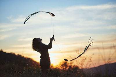 Woman juggling at sunset. she's in a nice meadow in the country.