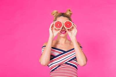 Midsection of woman holding sunglasses against yellow background