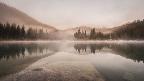 Scenic view of lake by trees against sky