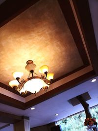 Low angle view of illuminated pendant lights hanging on ceiling