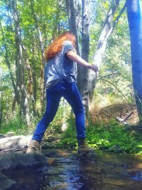 Woman standing on tree trunk in forest