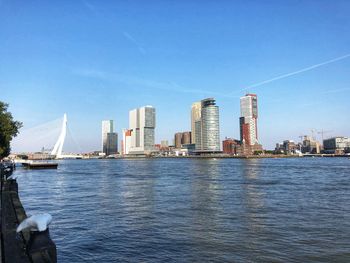 River by modern buildings against sky in city