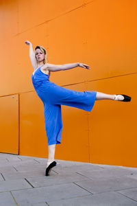 Full length of woman dancing against wall