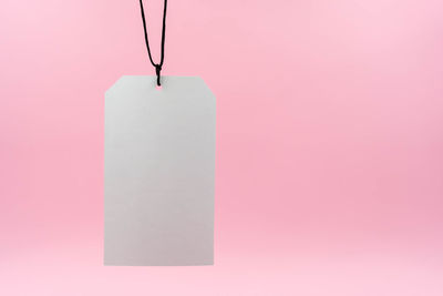Close-up of paper hanging against pink background