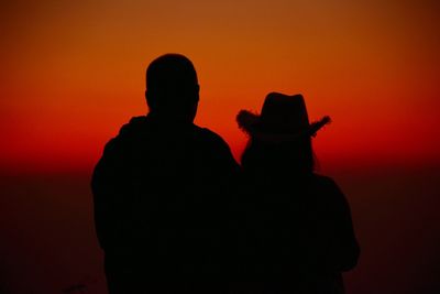 Silhouette couple against orange sky during sunset