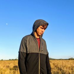Man wearing hat standing on field against clear sky