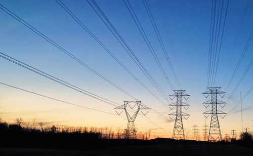 Low angle view of electricity pylon against sky at dusk