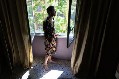 Woman looking through window at home