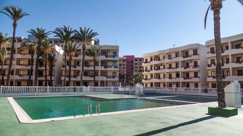 Swimming pool by buildings against sky in city