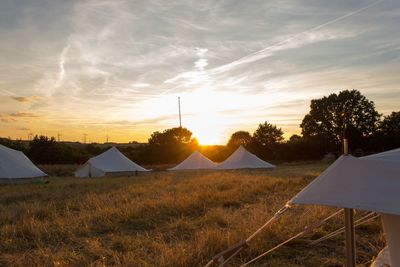 Tent on field against sky during sunset