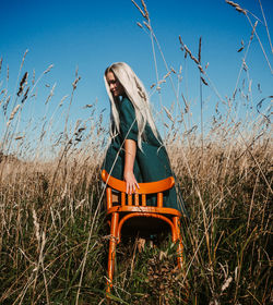 Beautiful woman with chair amidst grass