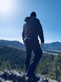 Rear view of man standing on mountain against clear sky