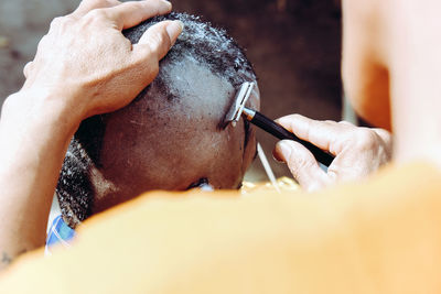 Close-up of man shaving head of boy
