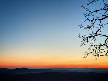 Scenic view of silhouette mountains against orange sky