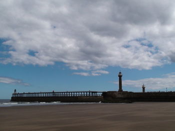 Pier on sea against cloudy sky