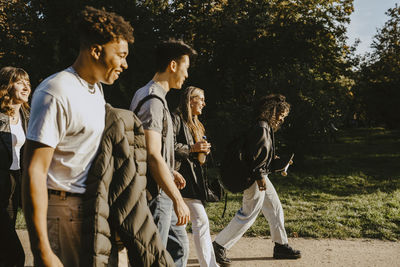 Happy male and female friends walking on road in park