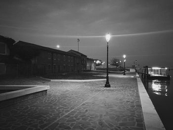 Illuminated street light against sky at night