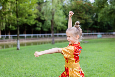 Young woman with arms raised standing on field