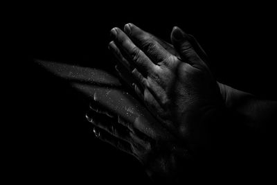 Close-up of hands against black background