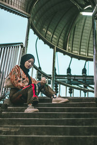 Low angle portrait of girl sitting on staircase