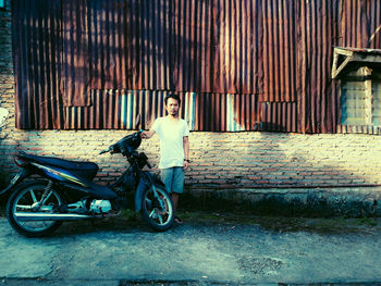 Full length portrait of boy standing on bicycle