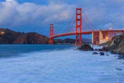 Golden gate bridge over river against cloudy sky