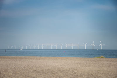 Wind turbines on beach against sky