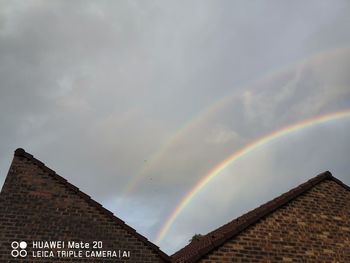 Low angle view of rainbow over building against sky