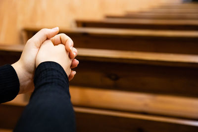 Cropped hands of woman praying in church