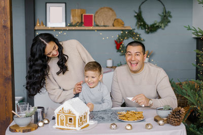 A stylish happy family decorates a gingerbread house