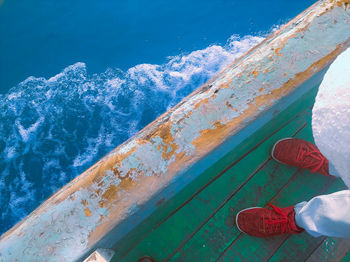 Low section of person standing on boat deck over sea
